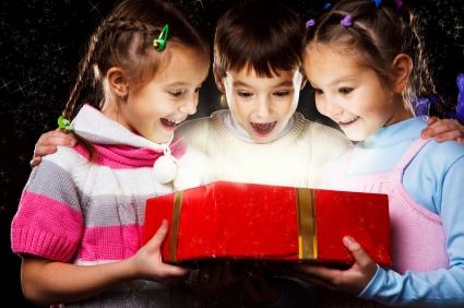 Three excited kids look happily into Christmas gift