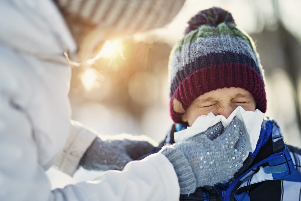 Mom blows kids nose with tissue during cold and flu season