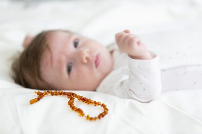 Baby lying next to an amber teething necklace